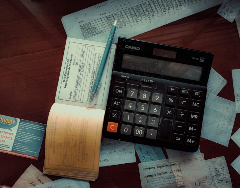 Calculator and financial documents comparing property management bookkeeping vs accounting tasks