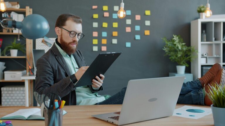 Man reviewing papers and laptop, a sign property management accounting help is needed
